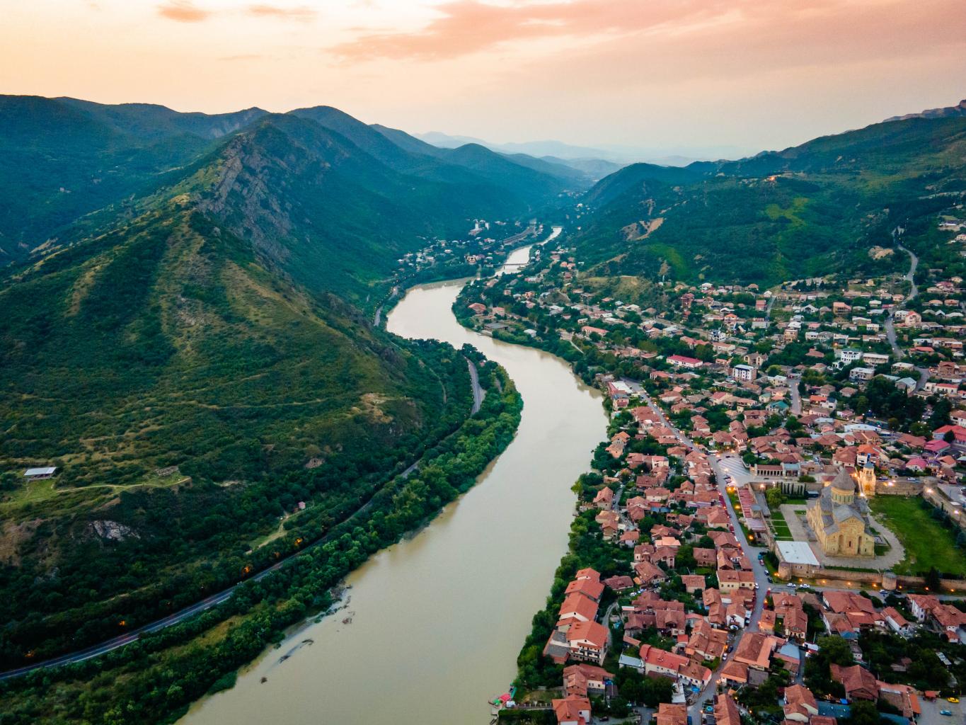 Aerial view of streets of Mtskheta village in Georgia with Svetitskhoveli Cathedral fortress along Mtkvari river